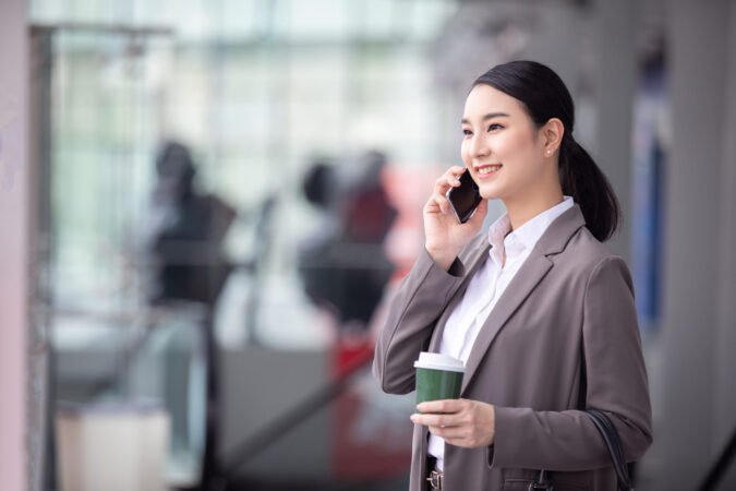 asian-woman-with-smartphone-standing-against-street-blurred-building