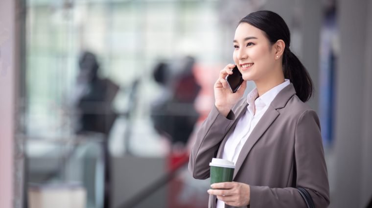 asian-woman-with-smartphone-standing-against-street-blurred-building asian-woman-with-smartphone-standing-against-street-blurred-building